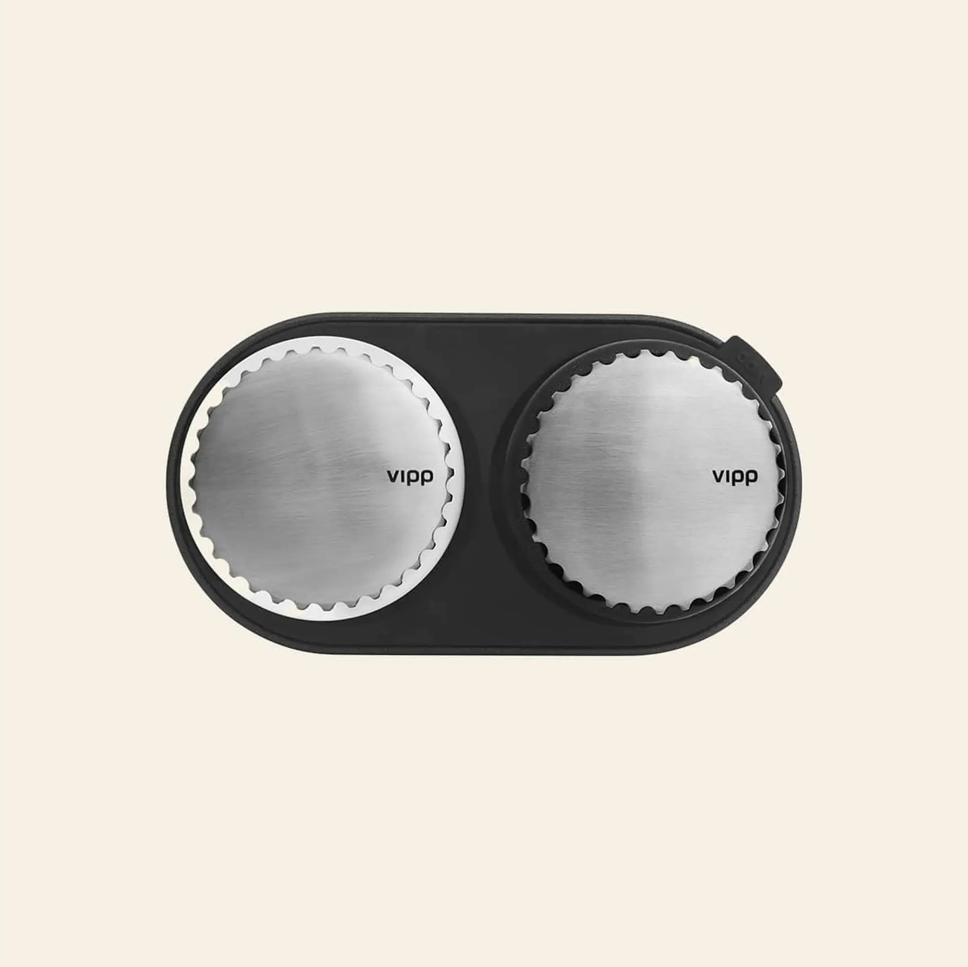 A top-down view of Vipp Vipp263 Salt & Pepper Mills with stainless steel tops and ceramic grinders, elegantly arranged in a black oval tray on a light beige background—an ideal addition to any modern kitchen.
