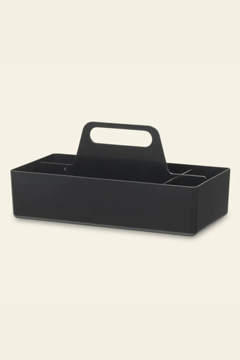 The Vitra Toolbox RE by Vitra is a black rectangular caddy with a central handle and multiple compartments, crafted from recycled ABS plastic and shown on a plain light background.