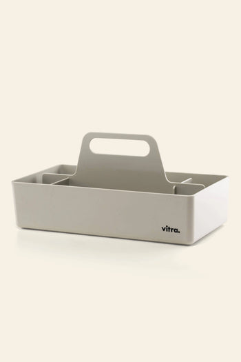The Vitra Toolbox RE by Vitra is a white rectangular caddy made from recycled ABS plastic, featuring a central handle, multiple compartments, and the Vitra logo on the front.