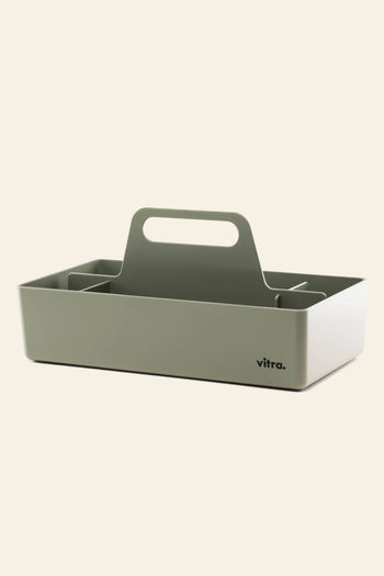 The Vitra Toolbox RE by Vitra is a rectangular, light gray storage caddy made of recycled ABS plastic with a central handle, multiple compartments, and the Vitra logo on one side, shown against a plain, light background.