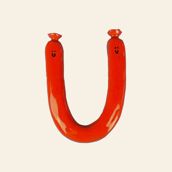 The Wobbly Studio Happy Saucisse Wall Decor is a handcrafted red, U-shaped sausage with smiling faces at each end, adding a fun, unique touch to your space and standing out beautifully against light backgrounds.