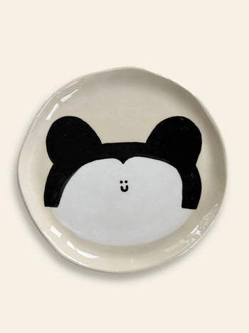The Wobbly Studio Happy Things Plate - Souris is a cream-colored ceramic plate with a simple round animal face, black ears, and a small smiling mouth, from Wobbly Studios Happy Things collection.