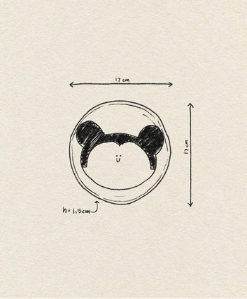 A hand-drawn illustration of the Wobbly Studio Happy Things Plate - Souris, a round plate with a bear face and ears, 17 cm wide/tall and 1.5 cm deep, labeled with measurement arrows on a textured beige background.