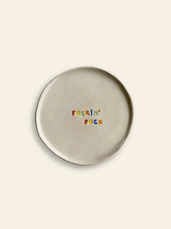 The Wobbly Studio Mini Plate - Fuckin Fuck is a handcrafted white ceramic plate featuring FUCKIN FUCK in colorful letters—a playful, bold piece by Wobbly Studio for fans of cheeky designs.
