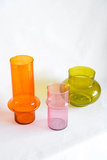 Three modern glass vases in orange, pink, and green from Wonderland Botanicals’ Paprika collection are arranged on a white surface, their geometric shapes and translucent finish capturing the collaboration’s bold, colourful style.