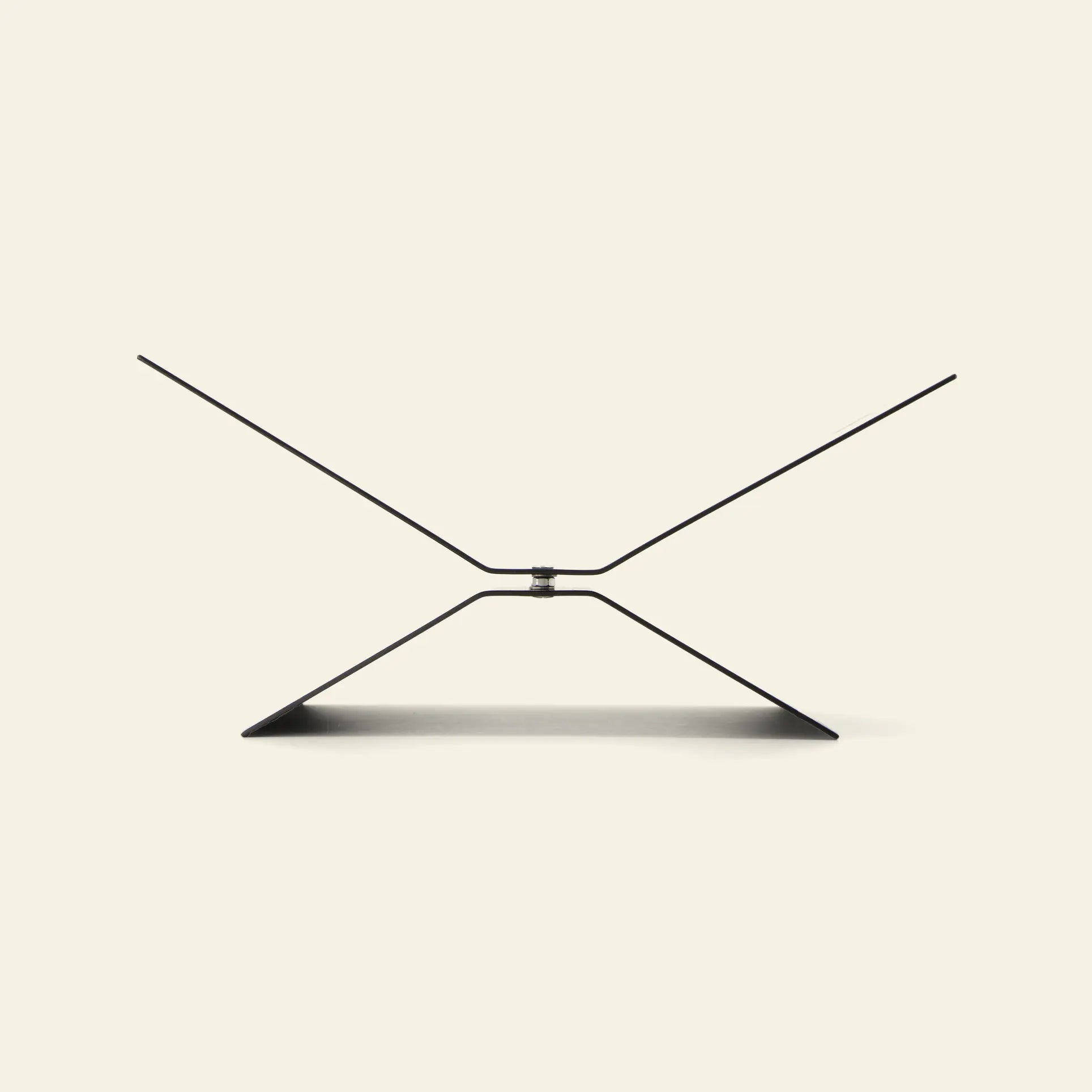 The baebsy Atlas Bookstand features a minimalist, geometric X-shaped design that appears to float above a plain light background, with the stand casting a gentle shadow underneath.