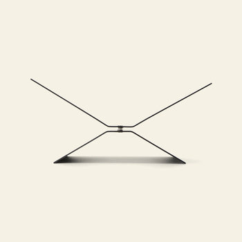 The baebsy Atlas Bookstand features a minimalist, geometric X-shaped design that appears to float above a plain light background, with the stand casting a gentle shadow underneath.