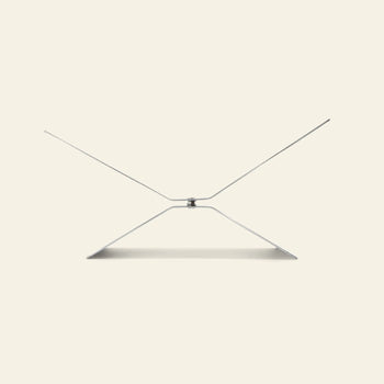The baebsy Atlas Bookstand by baebsy is a minimalist silver metal stand with a geometric, angular levitation design, shown against a plain light beige background.