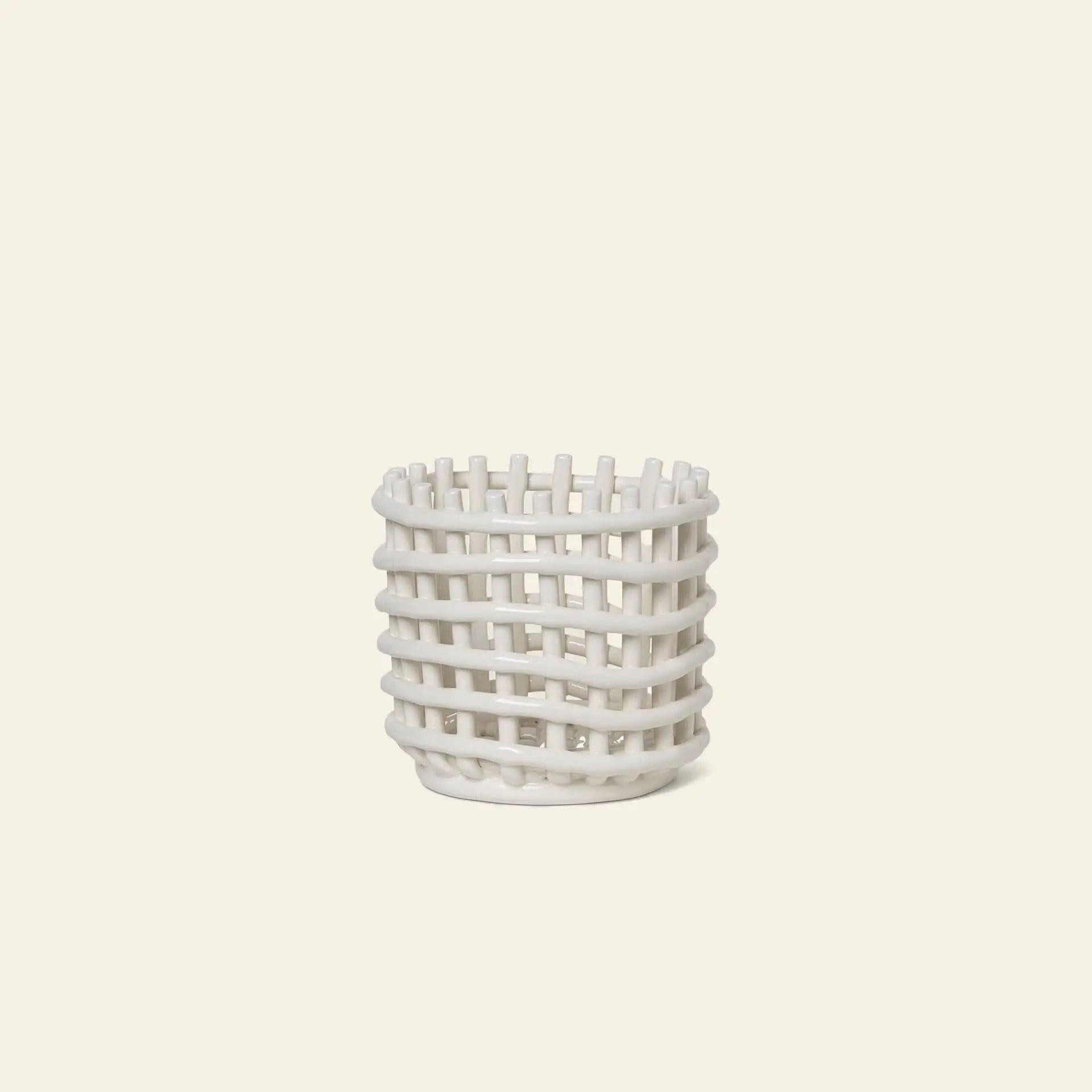 The ferm LIVING Ceramic Basket, Small, by ferm LIVING, features a white open-weave lattice design—ideal for chic storage—displayed on a plain light beige background.