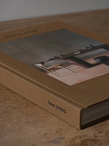 The ferm LIVING Coffee Table Book 2023 features a brown textured hardcover and minimalist interior photos, capturing the brand’s design concept and creative process, with ferm LIVING printed on the spine.