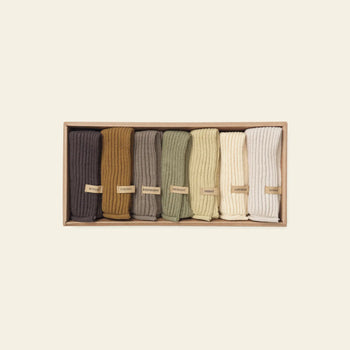 The ferm LIVING Day Cloths, Set of 7, features seven soft cloths in earth tones. Each is neatly rolled and labeled, crafted from organic cotton with GOTS certification—offering comfort and sustainable style from ferm LIVING.