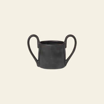 The ferm LIVING Flow Mug Mini is a dark, matte-finish ceramic childrens mug with two large handles, featuring modern design—ideal for stylish tableware collections and shown against a plain light beige background.
