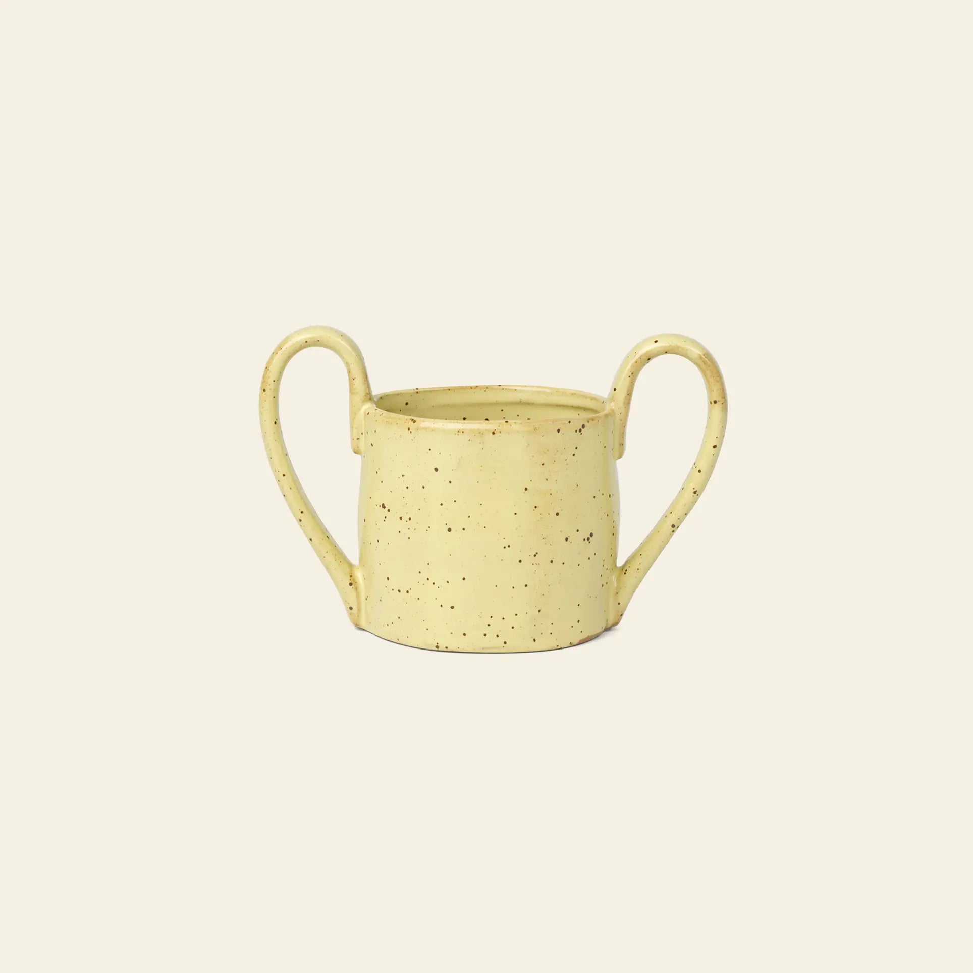 The ferm LIVING Flow Mug Mini by ferm LIVING is a yellow speckled ceramic cup with three curved handles, featuring modern design tableware on a plain light beige background.