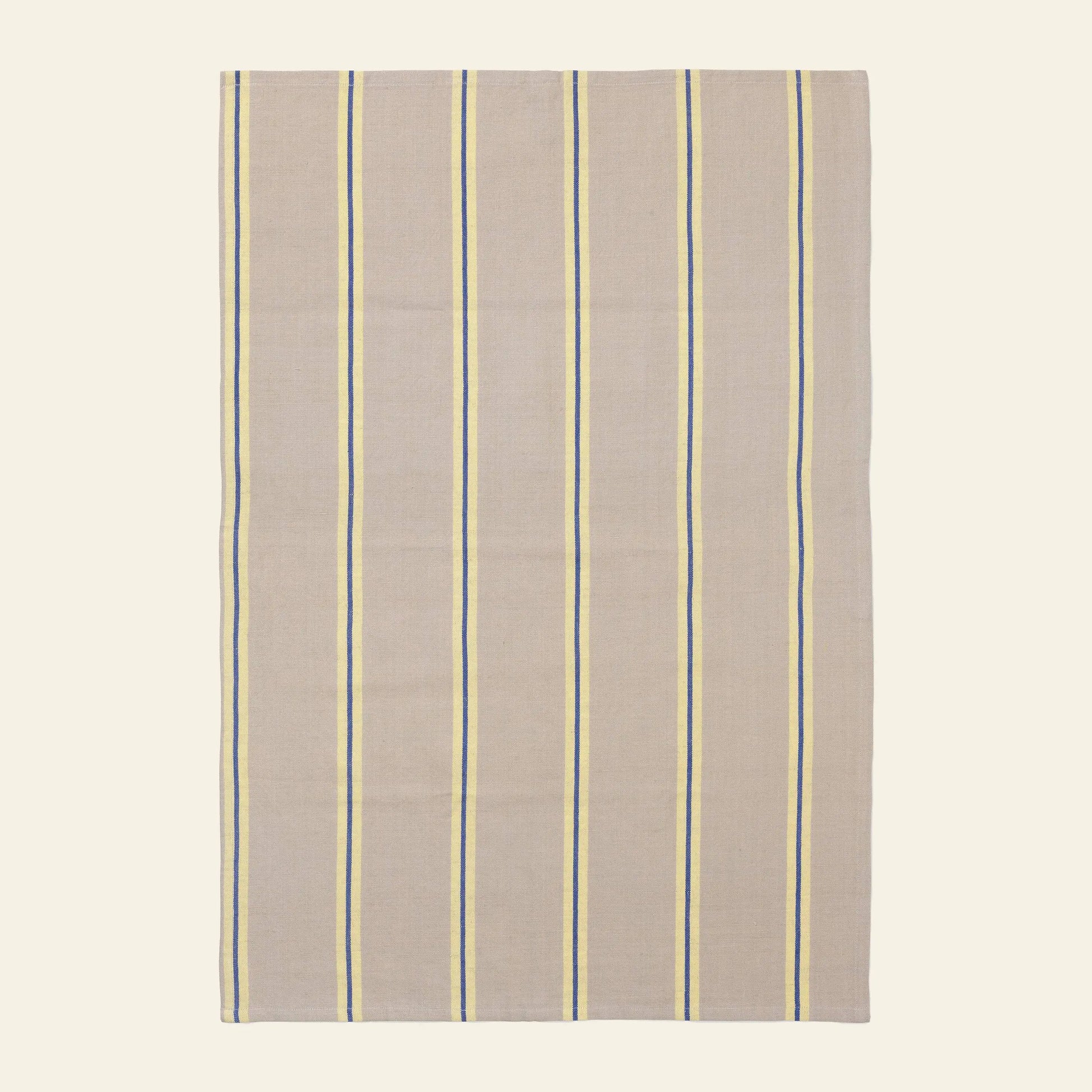 The ferm LIVING Hale Tea Towel by ferm LIVING features a rectangular beige fabric with evenly spaced vertical blue and yellow stripes, shown flat on a light background.