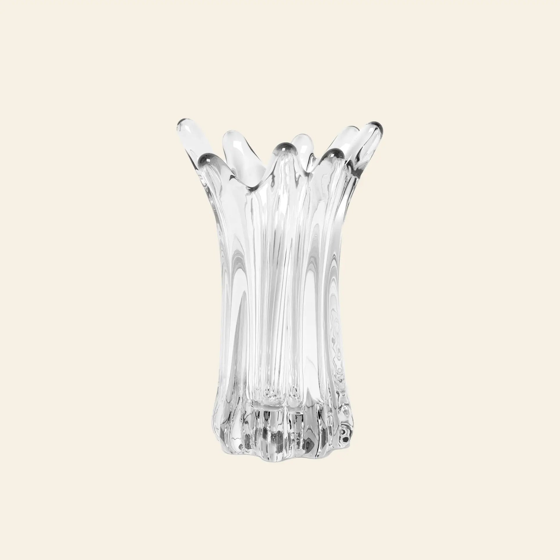 The ferm LIVING Holo Vase features an abstract, fluted design with wavy, organic edges. This clear glass vase from ferm LIVING stands upright against a simple, light backdrop, highlighting its expert craftsmanship.