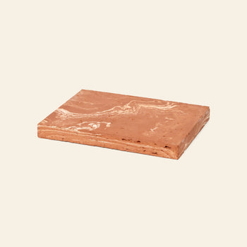 A rectangular bar of marbled brown chocolate sits on the ferm LIVING Merge Trivet by ferm LIVING, set against a plain light background.