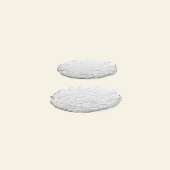 Two large, round Momento Glass Stones by ferm LIVING rest against a light beige backdrop, with one positioned slightly above and behind the other for a subtle layered look—showcasing their versatile design in any space. Set of 2.