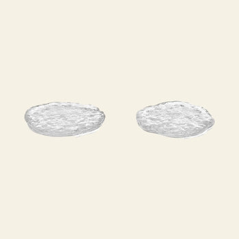 The ferm LIVING Momento Glass Stones S, Set of 2 by ferm LIVING are elegantly displayed side by side on a plain, light beige background, evoking a sophisticated touch reminiscent of decorative glass stones.