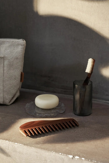 The ferm LIVING Momento Glass Stones S, Set of 2, rest elegantly on a decorative tray atop a stone countertop, adding sophisticated charm to the space in soft, natural light.
