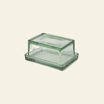 The ferm LIVING Oli Box, a rectangular green-tinted butter dish with matching lid made from recycled glass by ferm LIVING, is displayed on a plain beige background.