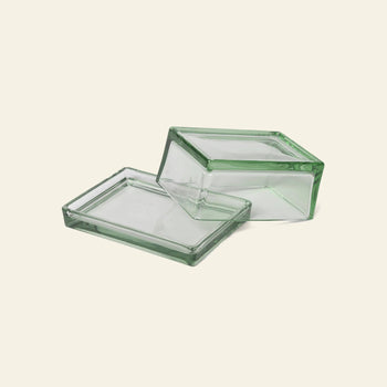 The ferm LIVING Oli Box set features two rectangular, clear recycled-glass containers with subtle green-tinted edges—one flat, one angled on top—creating a versatile storage solution against a light background.