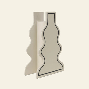 The ferm LIVING Paste Vase, Curvy by ferm LIVING features a wavy, abstract ceramic silhouette with a black outline on a smooth off-white surface, set against a plain beige background.