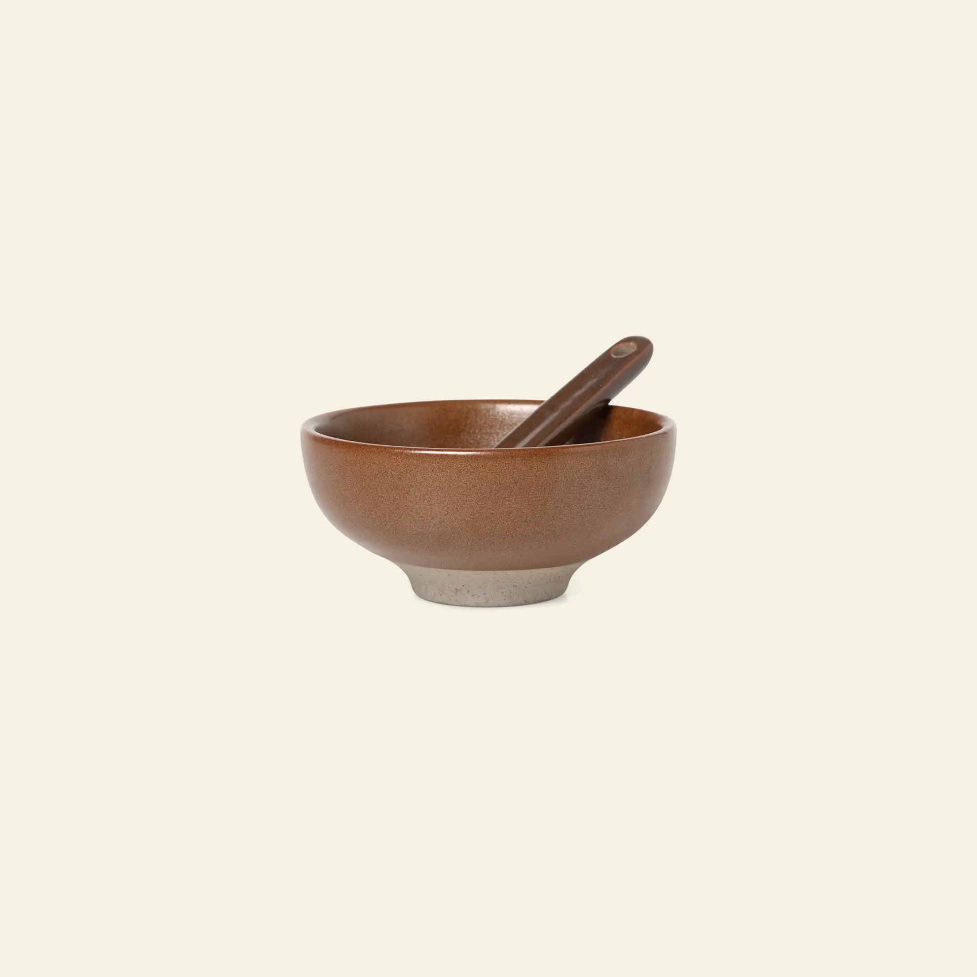 The ferm LIVING Petite Salt Set includes a brown ceramic bowl with a matching spoon, both featuring a smooth matte finish and lighter base—a stylish kitchen essential from ferm LIVING.