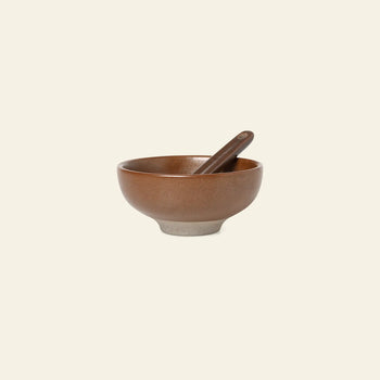 The ferm LIVING Petite Salt Set includes a brown ceramic bowl with a matching spoon, both featuring a smooth matte finish and lighter base—a stylish kitchen essential from ferm LIVING.