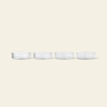 The ferm LIVING Ripple Serving Bowls, Set of 4, crafted from mouth-blown glass, feature a textured surface and elegant design. Each clear bowl is displayed in a row on a light beige background.