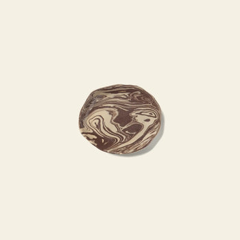 The ferm LIVING Ryu Platter, 18.5cm, by ferm LIVING, features a round design with swirled chocolate and vanilla tones inspired by the Nerikomi technique, displayed on a plain light beige background.