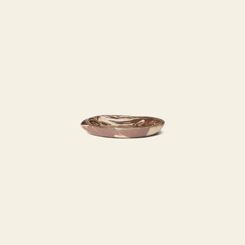 The ferm LIVING Ryu Platter, 18.5cm, features a small, shallow ceramic design with a brown and cream marbled pattern crafted using the Nerikomi technique, displayed on a plain light beige background.