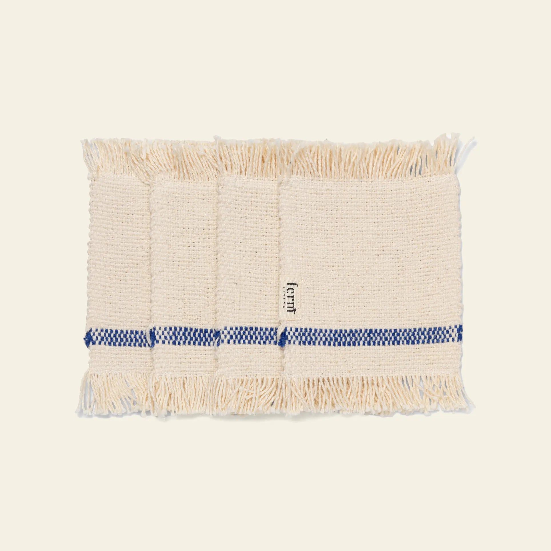The ferm LIVING Savor Coasters, Set of 4, are beige woven coasters with fringed edges, each featuring a blue checkered stripe on one side and a small ferm label.
