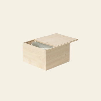 A light wooden box with a sliding lid, partially open to reveal the ferm LIVING Serena Bowl, 12.5cm inside, set against a plain off-white background.