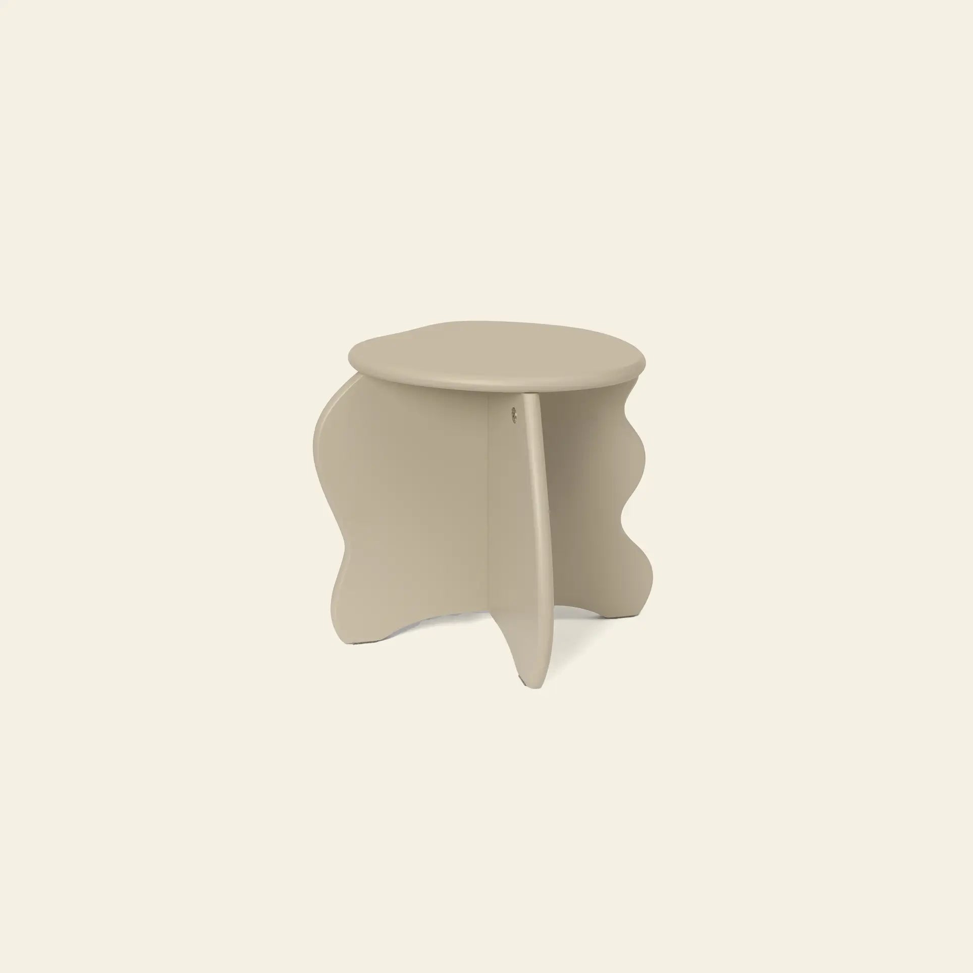 The ferm LIVING Slope Stool is a small, beige side table with a round top and sculptural wavy legs, crafted from FSC certified MDF—an organic yet modern piece by ferm LIVING, shown against an off-white background.