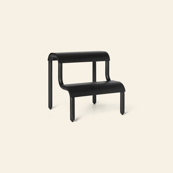 The ferm LIVING Up Step Stool by ferm LIVING is a modern black stool made of powder-coated iron, with two rounded textured steps and four cylindrical legs, displayed against a light beige background.