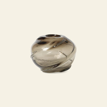The ferm LIVING Water Swirl Vase, Round is a handcrafted, mouth-blown vase featuring smoky glass, a glossy finish, and organic wavy contours set against a plain light background.