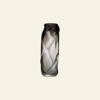 The ferm LIVING Water Swirl Vase, Tall, is a mouth-blown glass piece with a twisted cylindrical design and gradient color fading from dark to clear—perfect for displaying against a plain light background.