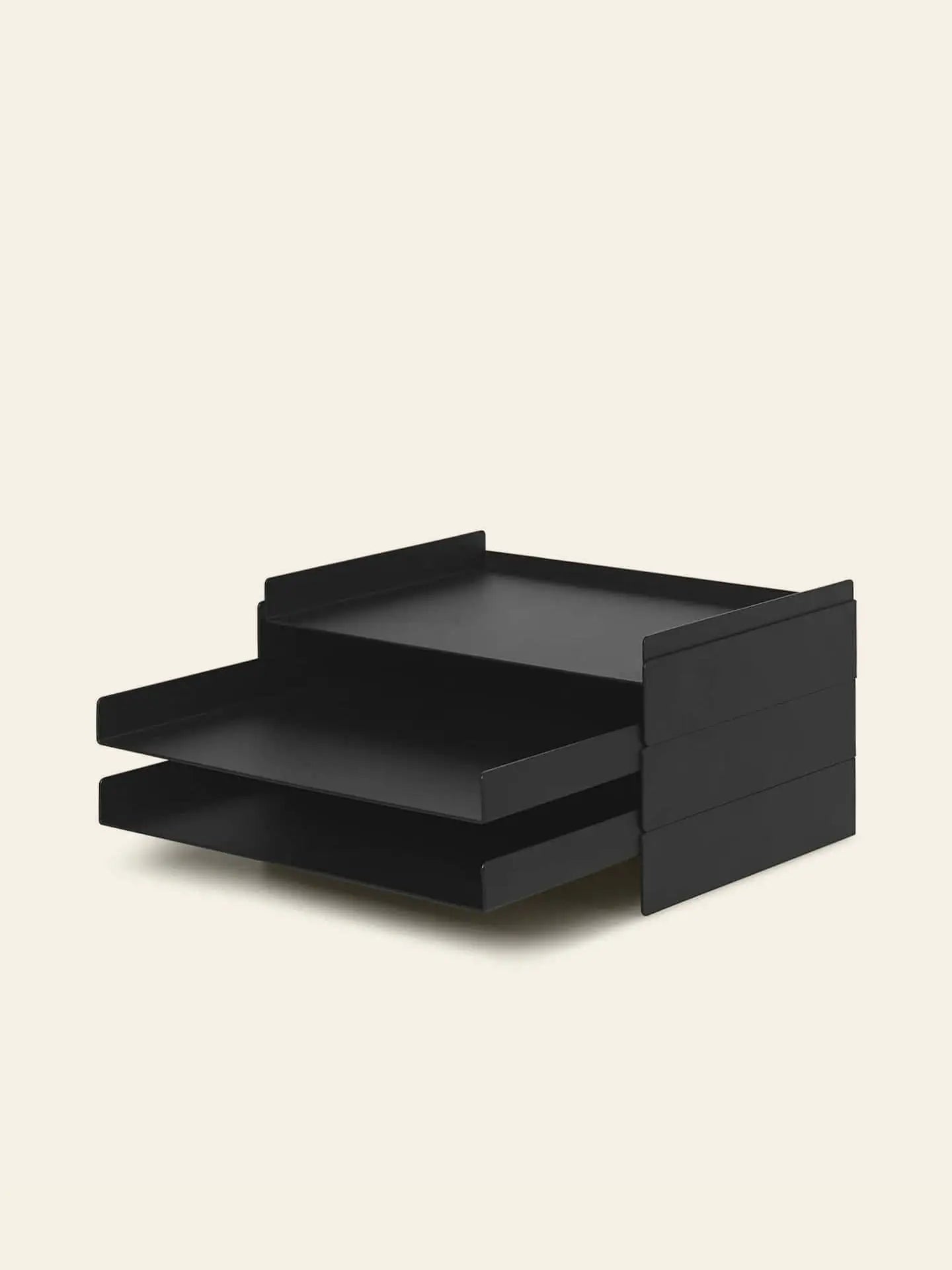 The ferm LIVING 2x2 Organizer, a black two-tiered tray with horizontal stackable compartments, keeps your desk tidy by holding papers or documents against a plain light background.