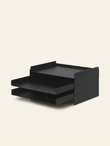 The ferm LIVING 2x2 Organizer, a black two-tiered tray with horizontal stackable compartments, keeps your desk tidy by holding papers or documents against a plain light background.
