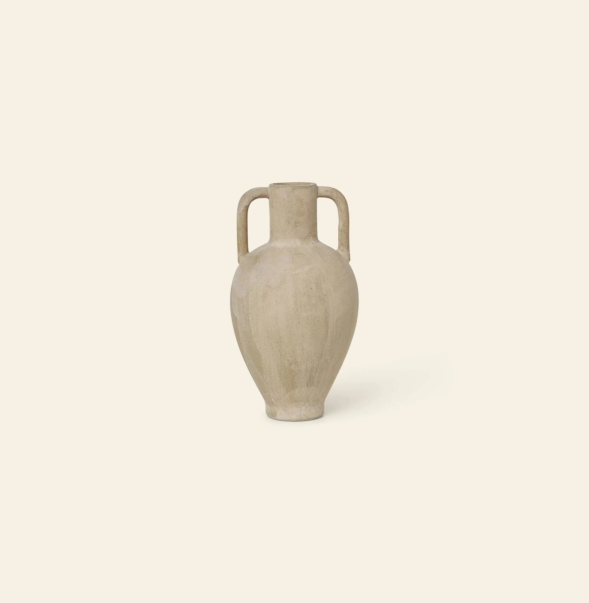 The ferm LIVING Ary Mini Vase L, a beige ceramic amphora inspired by ancient Greek vases with two vertical handles and a narrow neck, sits on a light cream background—crafted in textured glazed stoneware.