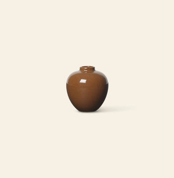 The ferm LIVING Ary Mini Vase S by ferm LIVING is a small, round, glossy brown ceramic vase with a short neck centered on a plain, light beige background—an elegant accent for any home decor.