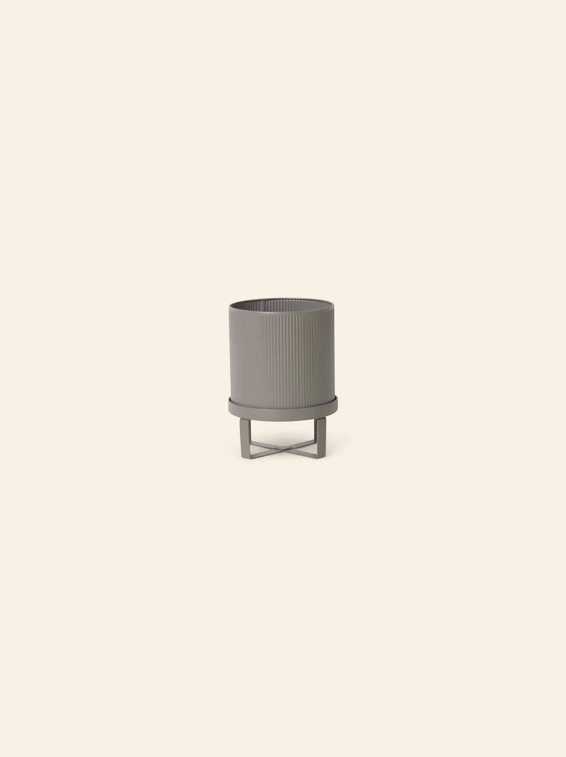 The ferm LIVING Bau Pot, Small, is a gray, round, ribbed modern pot with a matching stand inspired by Bauhaus architecture, shown against a plain light beige background.