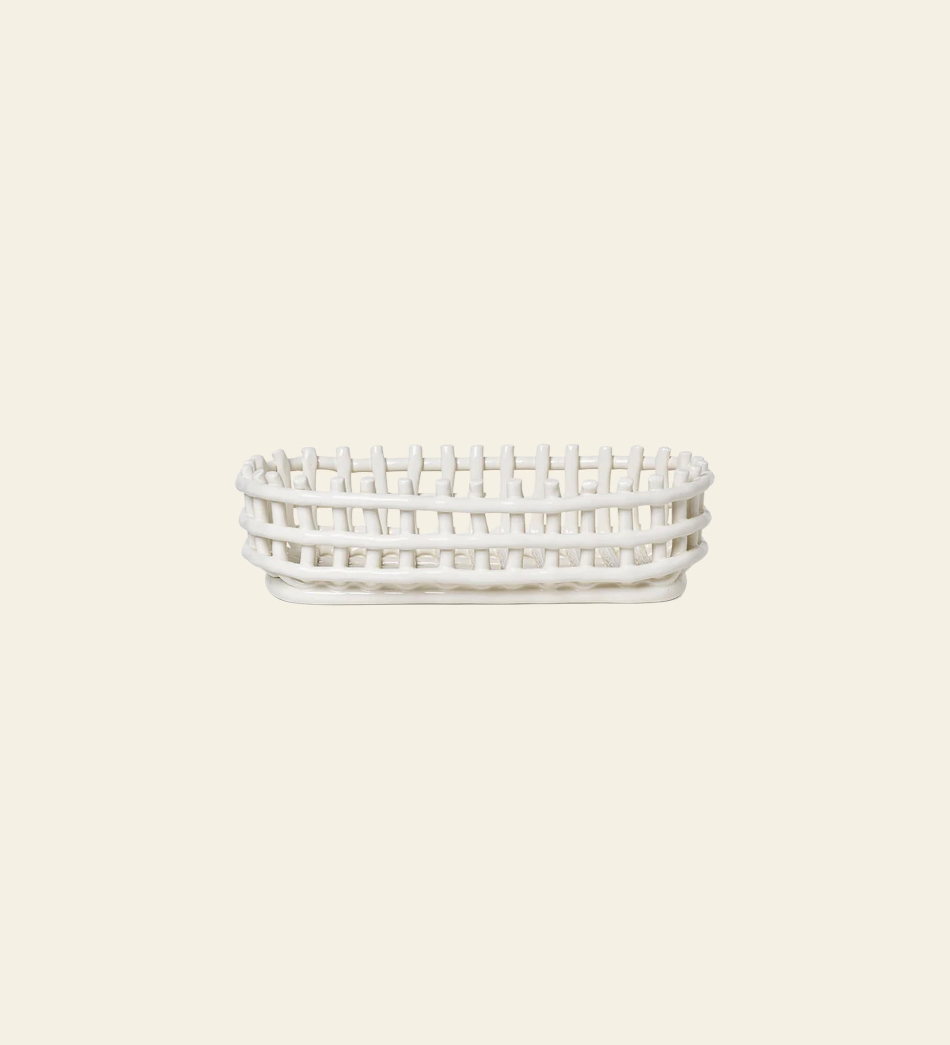 The ferm LIVING Ceramic Basket Oval features an open-weave, rectangular design with rounded edges and a modern look, shown from the side against a light beige background—a stylish storage solution by ferm LIVING for any space.
