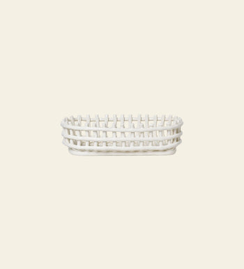 The ferm LIVING Ceramic Basket Oval features an open-weave, rectangular design with rounded edges and a modern look, shown from the side against a light beige background—a stylish storage solution by ferm LIVING for any space.