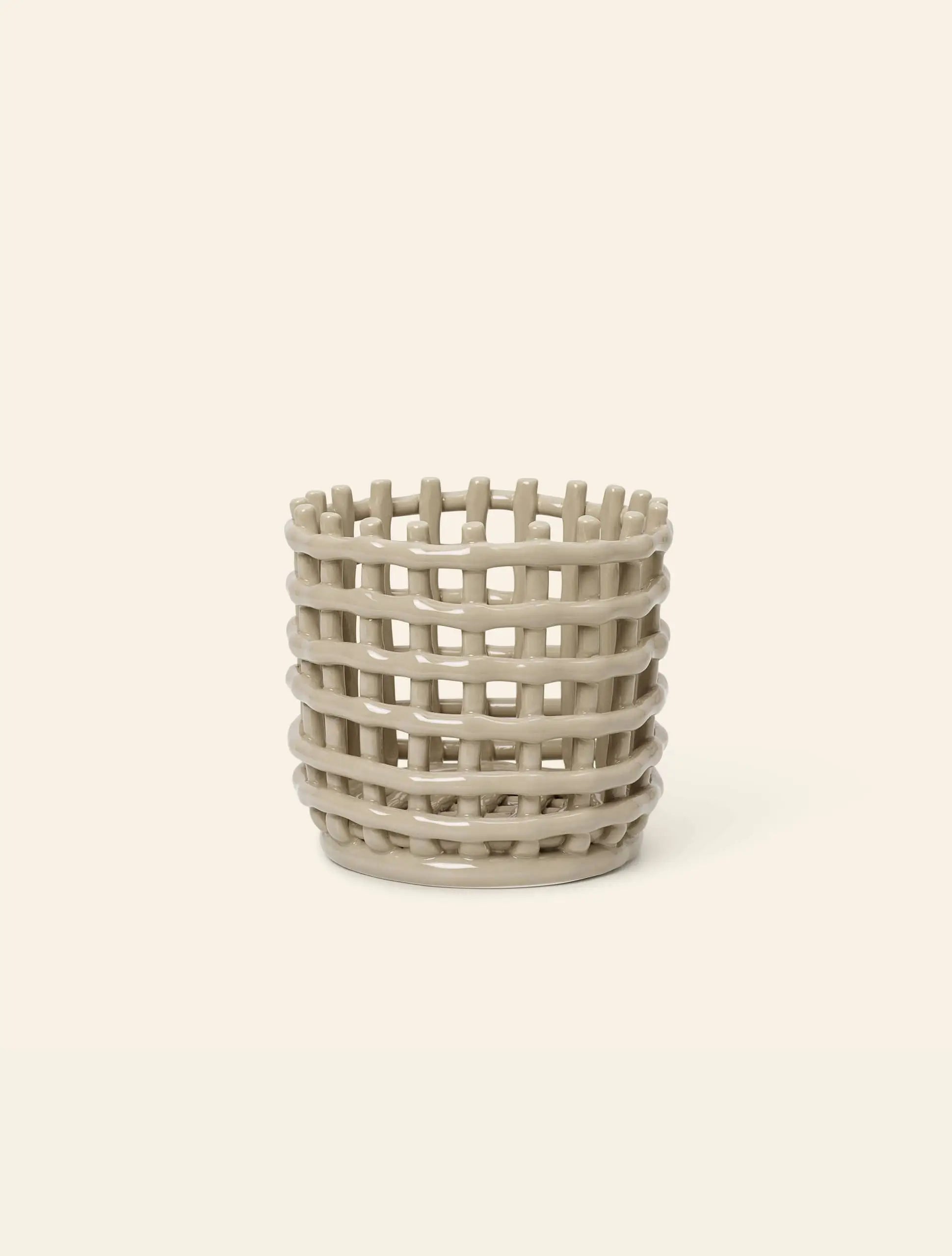 The ferm LIVING Ceramic Basket, Small, in beige with an open lattice design and glazed ceramic finish, offers charming storage from ferm LIVING against a plain light background.