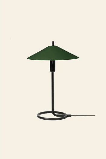 The ferm LIVING Filo Table Lamp pairs a circular black iron base, slim vertical stem, and wide dark green conical shade—an ideal modern home accent, shown here by ferm LIVING against a plain beige background.