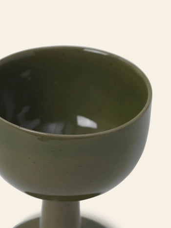 A close-up of the ferm LIVING Floccula Wine Glass in green, partially filled and set against a plain light background—capturing the charm of French bistros.