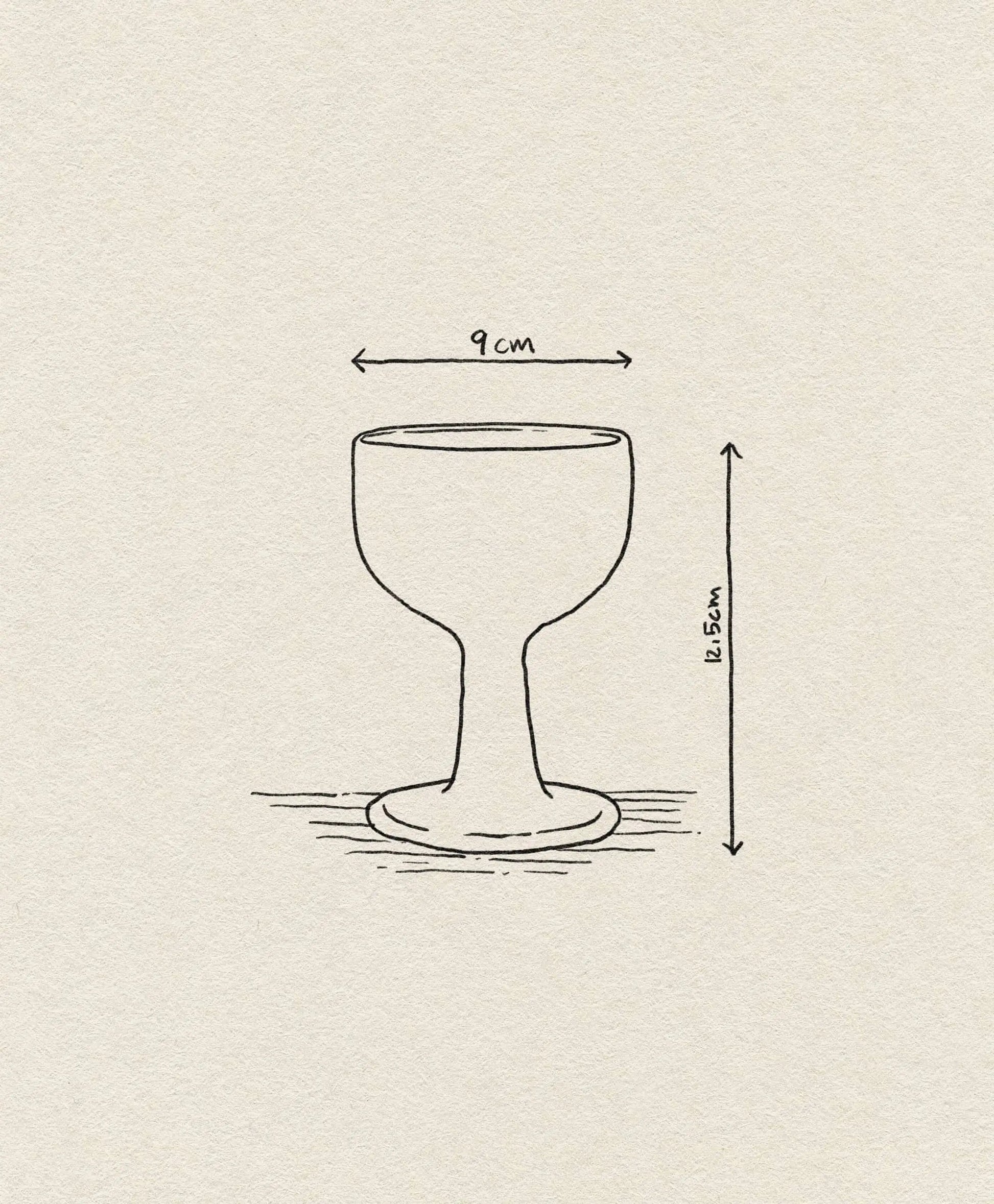 A simple line drawing of the ferm LIVING Floccula Wine Glass, featuring a wide 9 cm bowl and short stem, with a height of 11.5 cm. The design evokes classic French bistro styles and is set against lightly textured paper. Brand: ferm LIVING.