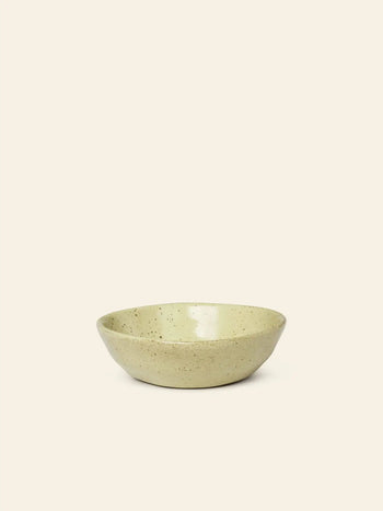 The ferm LIVING Flow Porcelain Bowl, Small, features a shallow, round shape and beige speckled finish, adding an artisanal touch to any table setting.