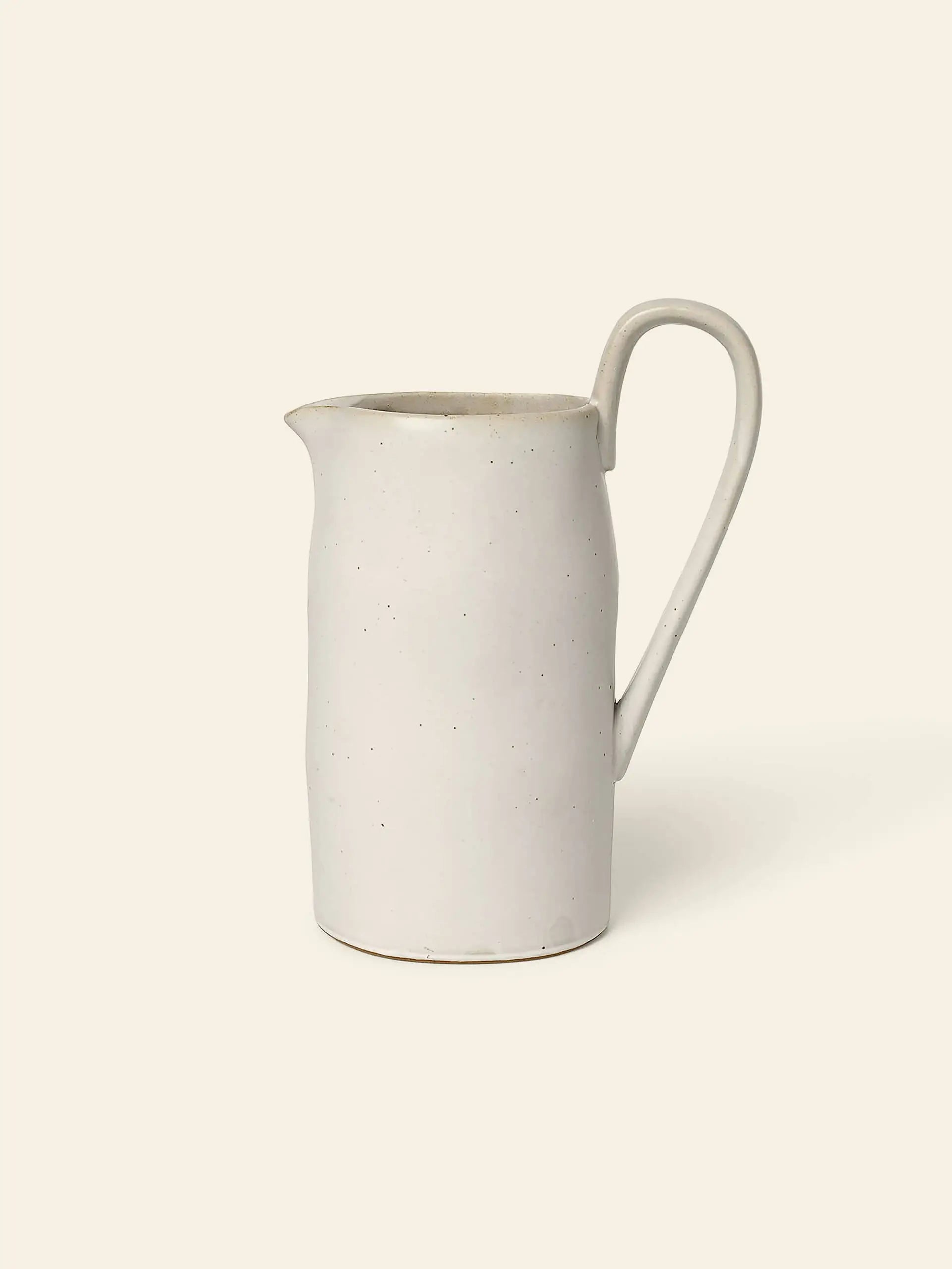 The ferm LIVING Flow Jug by ferm LIVING is a simple off-white ceramic piece with organic curves, a curved handle, and narrow spout—ideal for minimalist kitchen decor.
